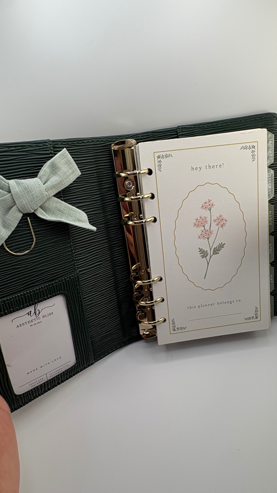 Deep olive binder open to a hey there welcome page with monthly dividers
